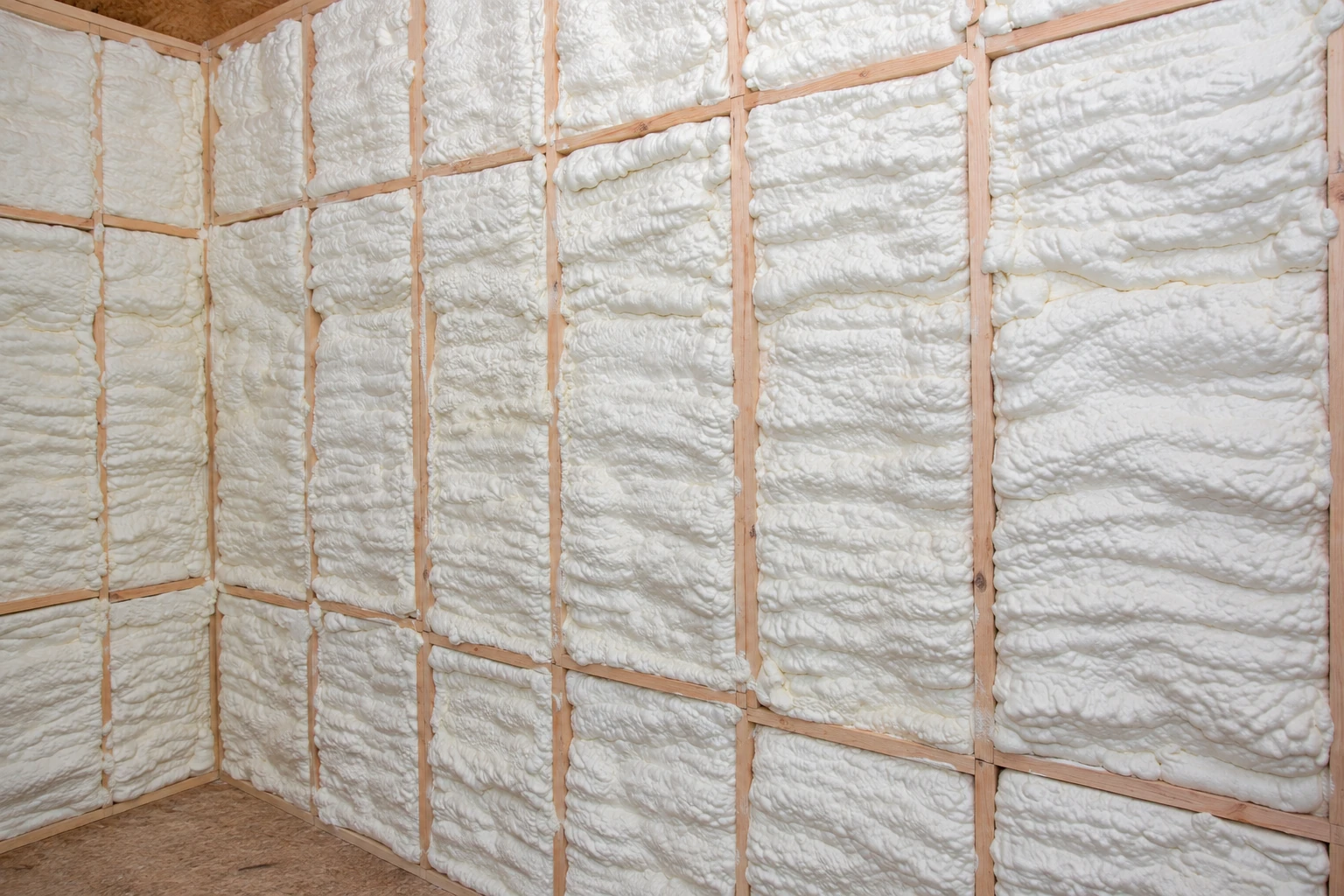 Wall framing filled with white spray foam insulation.